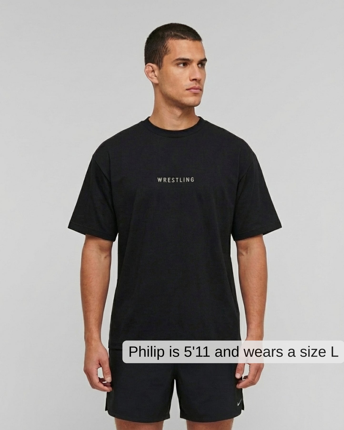 Man wearing a black t-shirt with 'Wrestling' text on a gray background